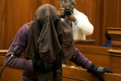Xolile Mngeni hides his face in court.