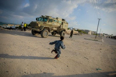 A young Somali girl runs in front of an African Union Mission in Somali (AMISOM) armed personnel carrier, Lido Beach in the Kaaraan District of Mogadishu, Somalia (file photo).