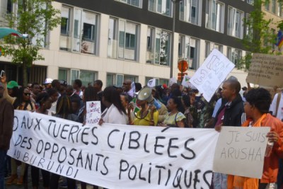 A chanting crowd protests in the streets of Bujumbura. The poster calls for an end to political killings in Burundi.