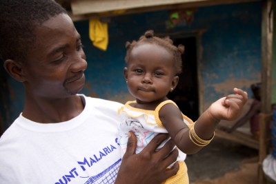 A Ghanaian volunteer who distributed malaria nets, with his daughter.