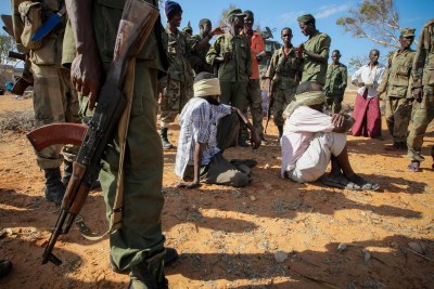 Alleged suspects of the extremist group Al-Shabaab are guarded by soldiers of the Somali National Army in Kismayo, Somalia in October 2012.