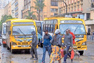 Commuters walk past matatus on the road within the city centre on December 4, 2018.
