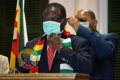 Health Minister Obadiah Moyo adjusts President Emmerson Mnangagwa's face mask at State House.
