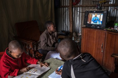 12-year-old Elizabeth and 10-year-old Justin follow a Social Studies lesson on the EDU TV while doing their revision at home in Kibera. Justin's brother, Morara who is in the kindergarten doodles on an exercise book. Elizabeth is in Standard 6 and Justin is in Standard 5, 