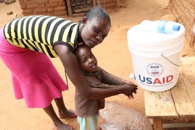 A Kenyan mother helps her son wash his hands.