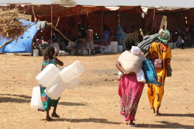 Recently arrived refugees from Tigray in Ethiopia bring supplies to help set up their shelter in Raquba camp, in Kassala, Sudan.