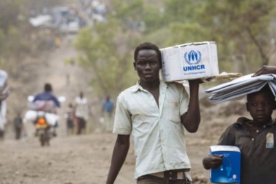 South Sudanese refugees carrying Core Relief Items walk down a road in Bidibidi refugee settlement, Yumbe District, Northern Region, Uganda.