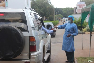 A health official disinfects people arriving at Wilkins Hospital, in Harare, May 12, 2021.