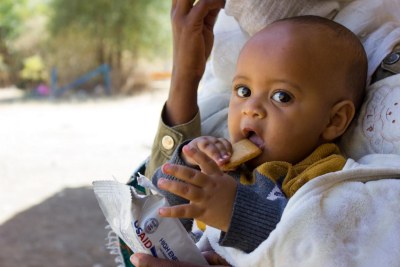 A small child eats a nutritious high-energy biscuit at a school that has been converted into a shelter in the Tigray region where the UN humanitarian agency OCHA estimates that 91 per cent of the population is in dire need of food assistance.