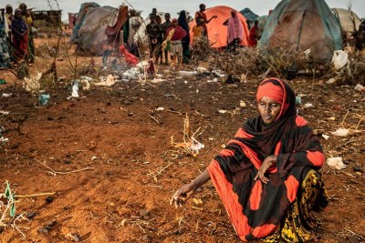 A mother sits at the unmarked graves of her two young children in a displaced persons camp in Dollow, Somalia.