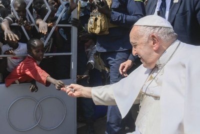 Outside the cathedral of Juba, a child gives Pope Francis a banknote during his trip to South Sudan in 2023.