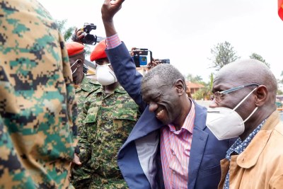 Dr Kizza Besigye flashes his political symbol to supporters and well-wishers on arrival in Makindye.