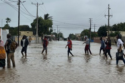 Local people walk in a flooded street after extreme rainfall in Xai Xai, in Gaza province, Mozambique.