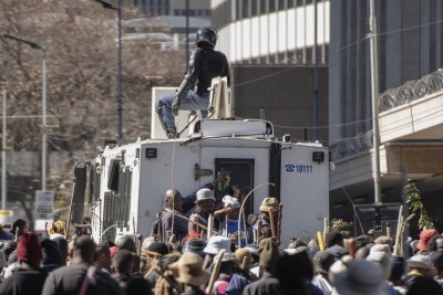 Protesters cling to the back of a police Nyala.